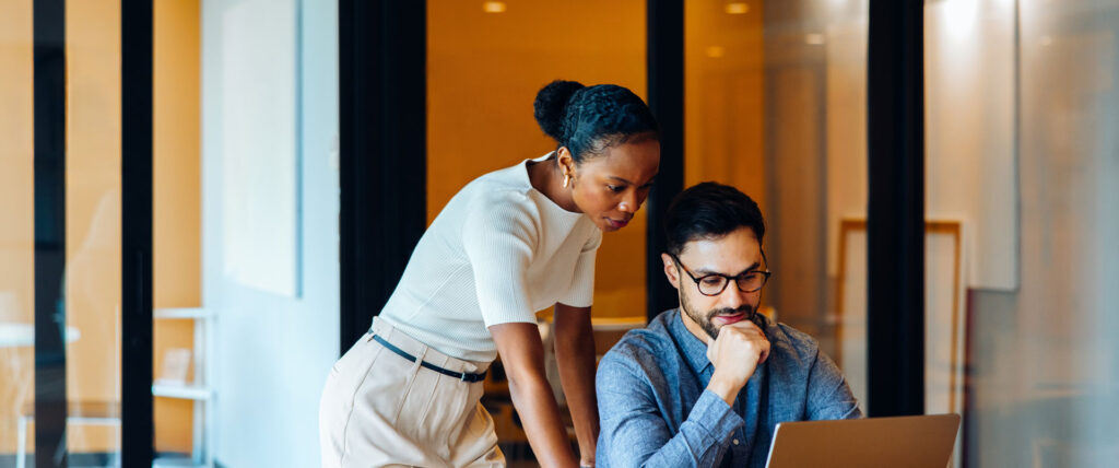Two professionals collaborating over a laptop.