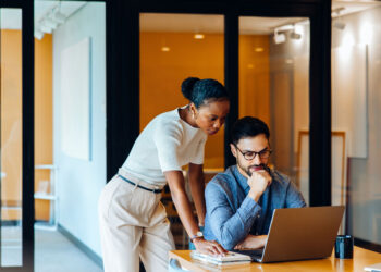 Two professionals collaborating at a laptop.